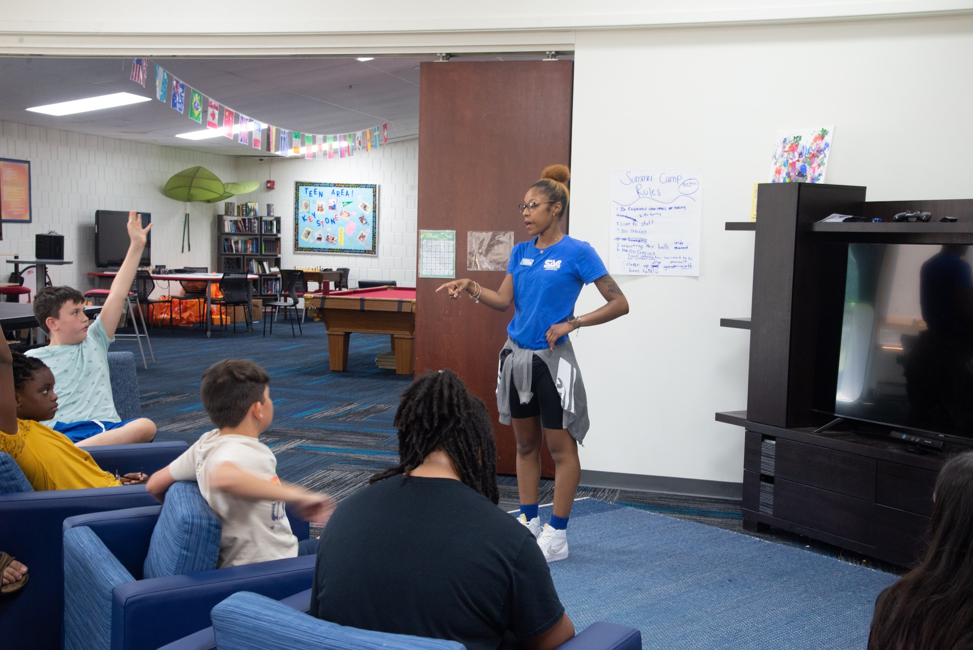 De’Shae Scott, youth programs assistant (middle), discusses what games and entertainment is available at the Prairies Youth Center (PYC) June 22. The PYC offers a wide variety of clubs and activities for youth ages 9 to 18. (U.S. Air Force photo by Airman 1st Class James Johnson)
