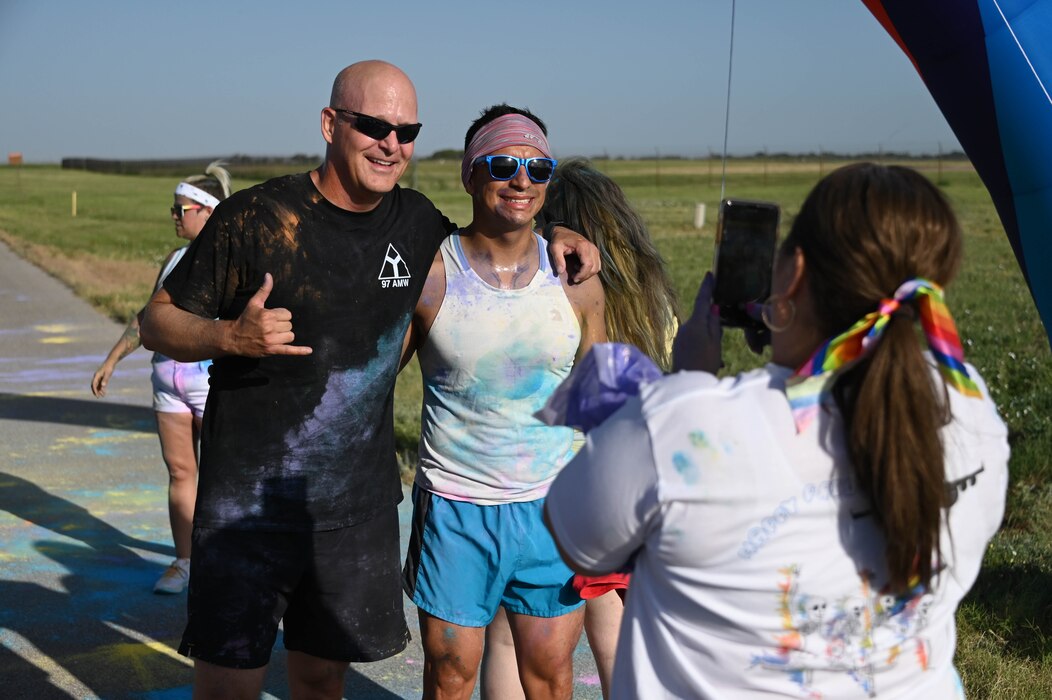Susan Bradford, 97th Air Mobility Wing (AMW) violence prevention integrator, takes a photo of U.S. Air Force Col. Blaine Baker (left), 97th AMW commander, and Chief Master Sgt. Caesar Flores, 97th AMW command chief, after the Pride Month color run at Altus Air Force, Oklahoma, June 24, 2022. The purpose of Pride Month is to recognize the impact that LGBTQ+ individuals have had on history locally, nationally, and internationally. (U.S. Air Force photo by Senior Airman Kayla Christenson)