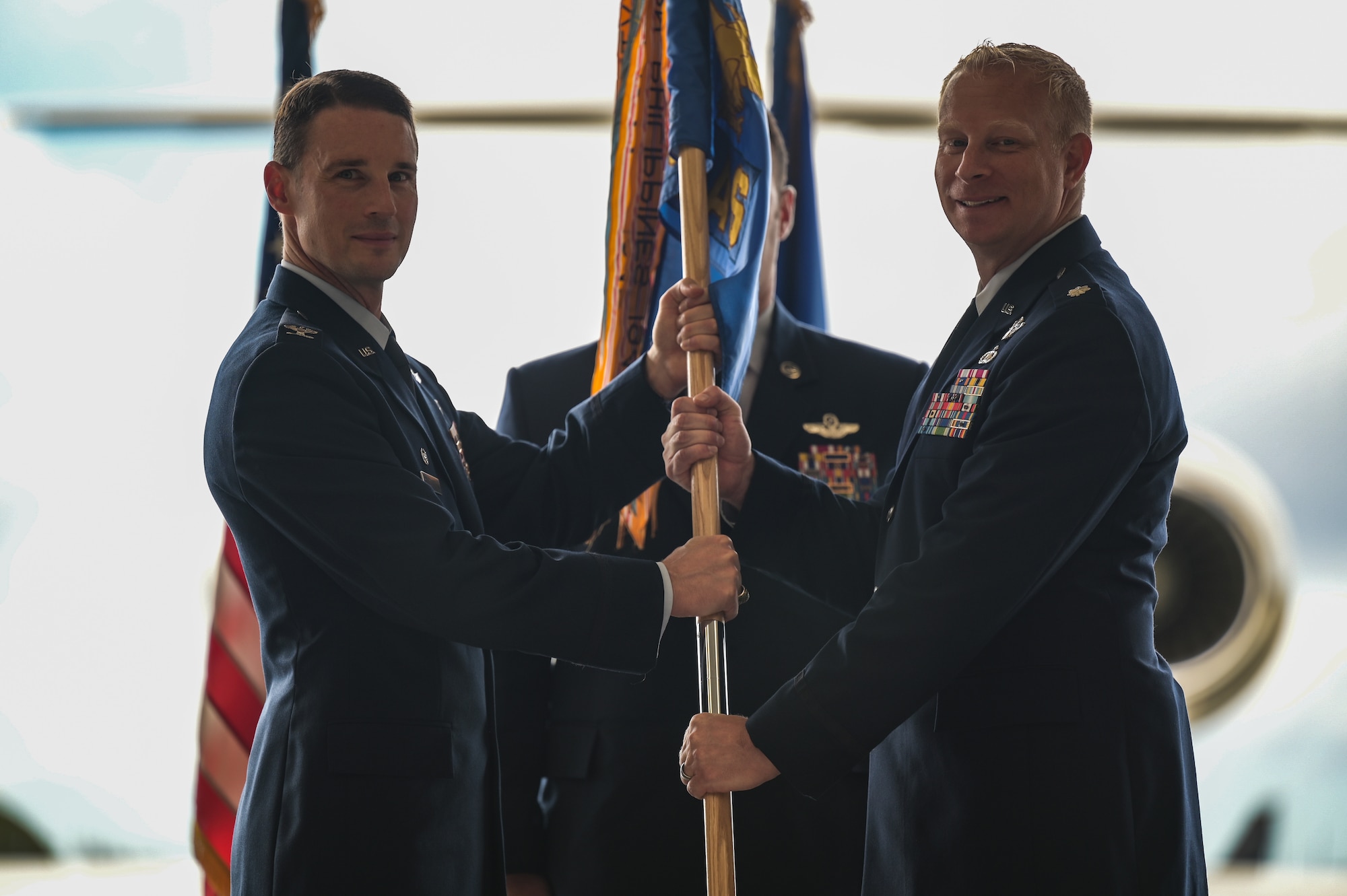 Lt. Col. Daniel Hellinger, 65th Airlift Squadron incoming commander, assumes command of the 65th AS by accepting the guidon from Col. Garrett Fisher, 15th Operations Group commander, during a change of command ceremony at Joint Base Pearl Harbor-Hickam, Hawaii, June 24, 2022. The 65th AS enables global airlift and communication between senior leaders throughout the Indo-Pacific area of responsibility. (U.S. Air Force photo by Staff Sgt. Alan Ricker)