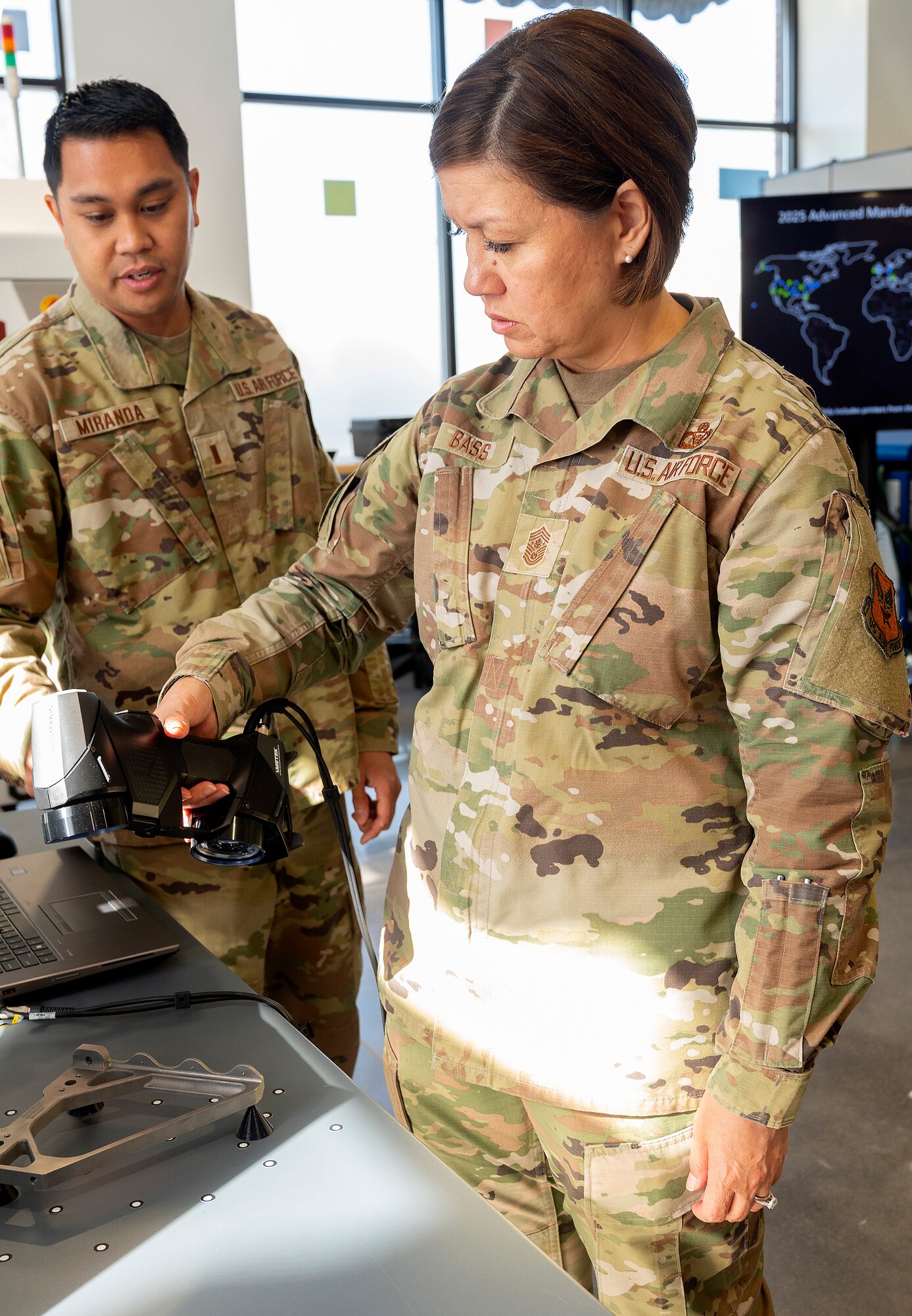 Air Force 2nd Lt. Lewis Miranda (left), Air Force Life Cycle Management Center Rapid Sustainment Office Advance Manufacturing Program, briefs Chief Master Sgt. of the Air Force JoAnne S. Bass on the digital scanning of parts for use in computer assisted design and 3D printing. Bass was in Dayton for the Corona Conference at Wright-Patterson Air Force Base and took the opportunity to learn about innovative programs in the area. (U.S. Air Force photo by R.J. Oriez)