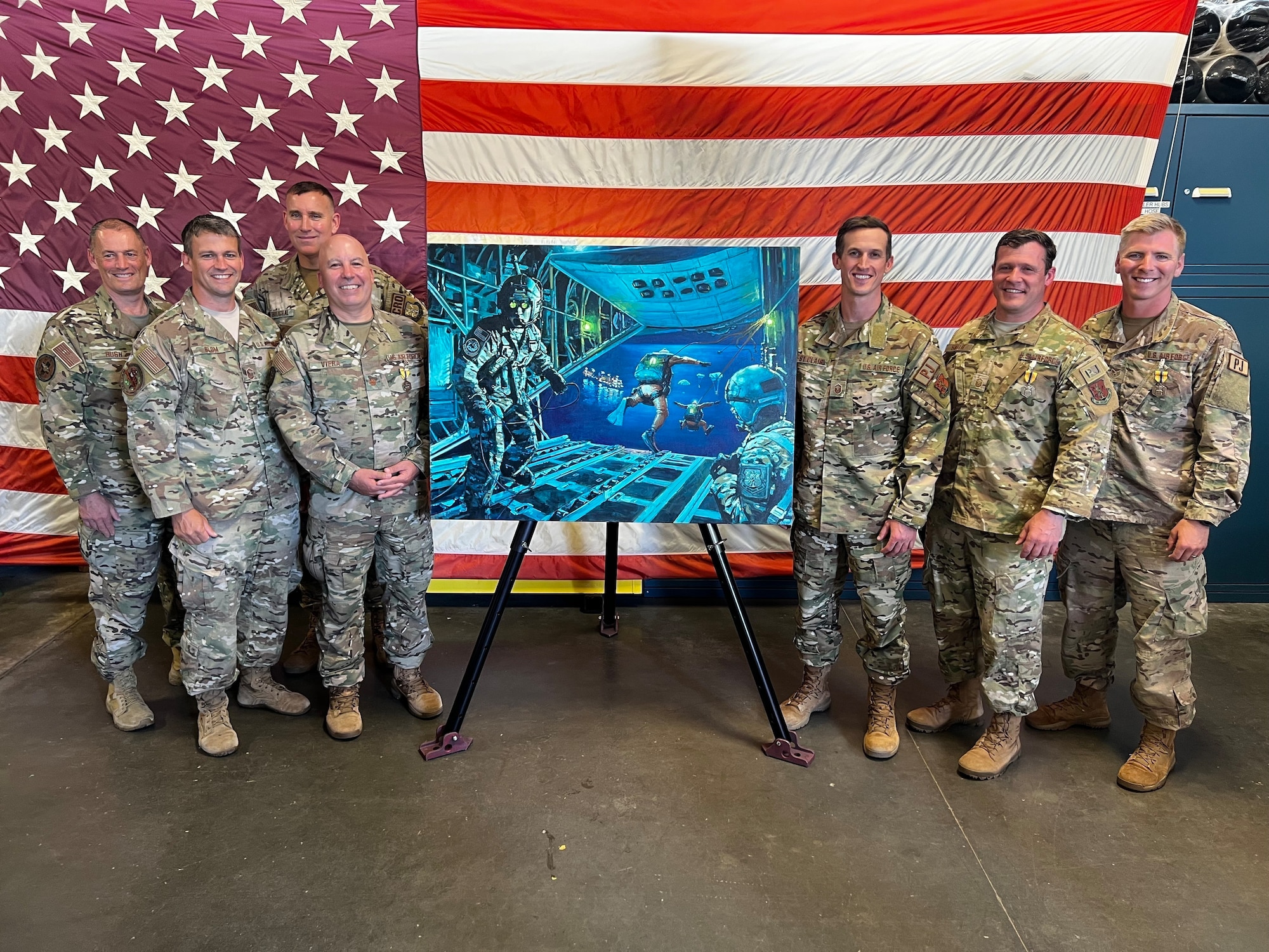 New York Air National Guard Airmen who were part of a 2017 mission to save two badly burned crewmen on board the Slovenian bulk carrier Tamar pose with a painting commemorating the mission during an awards ceremony June 4, 2022, at F.S. Gabreski Air National Guard Base in Westhampton Beach, New York.