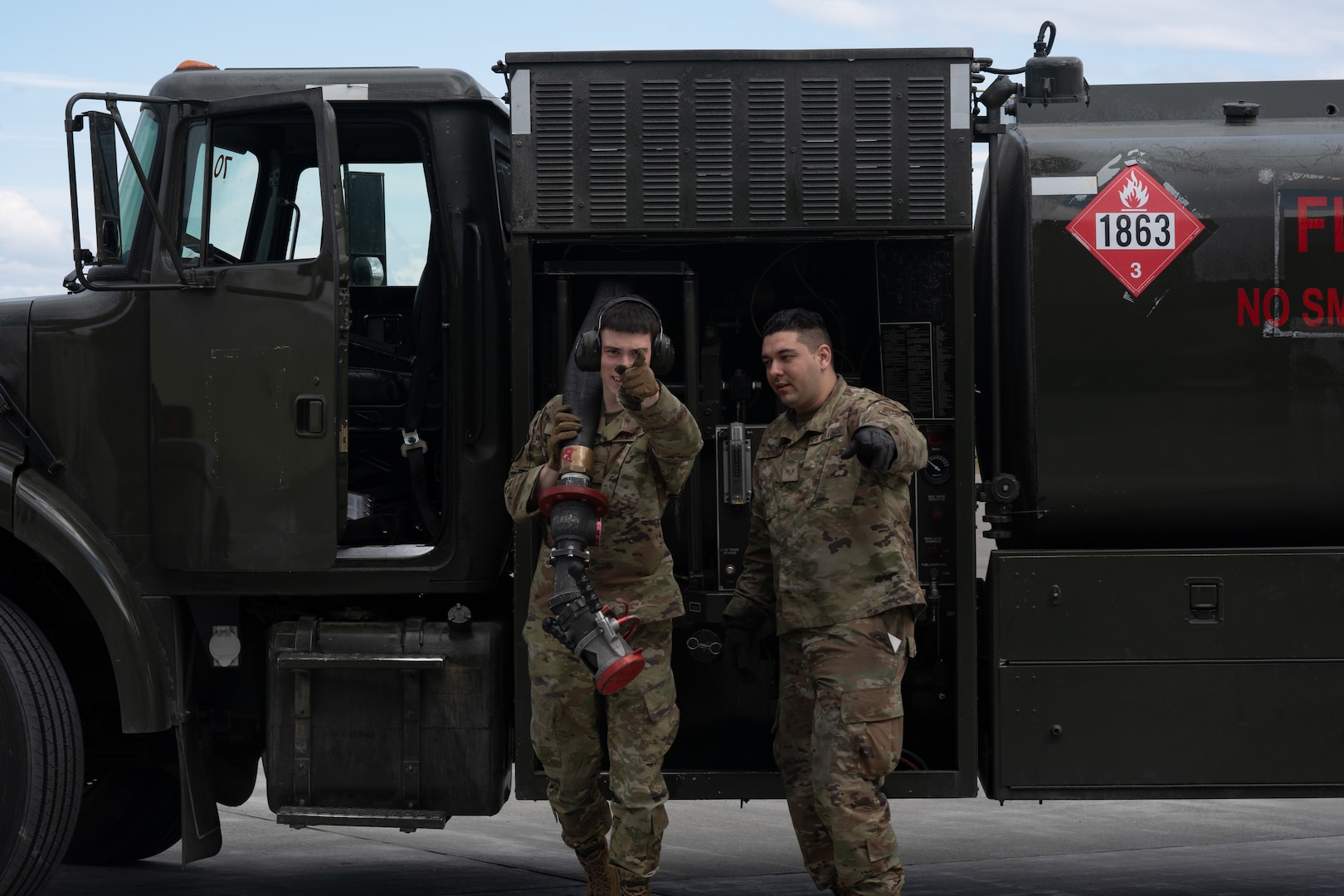 An Airman carries a large fuel hose.