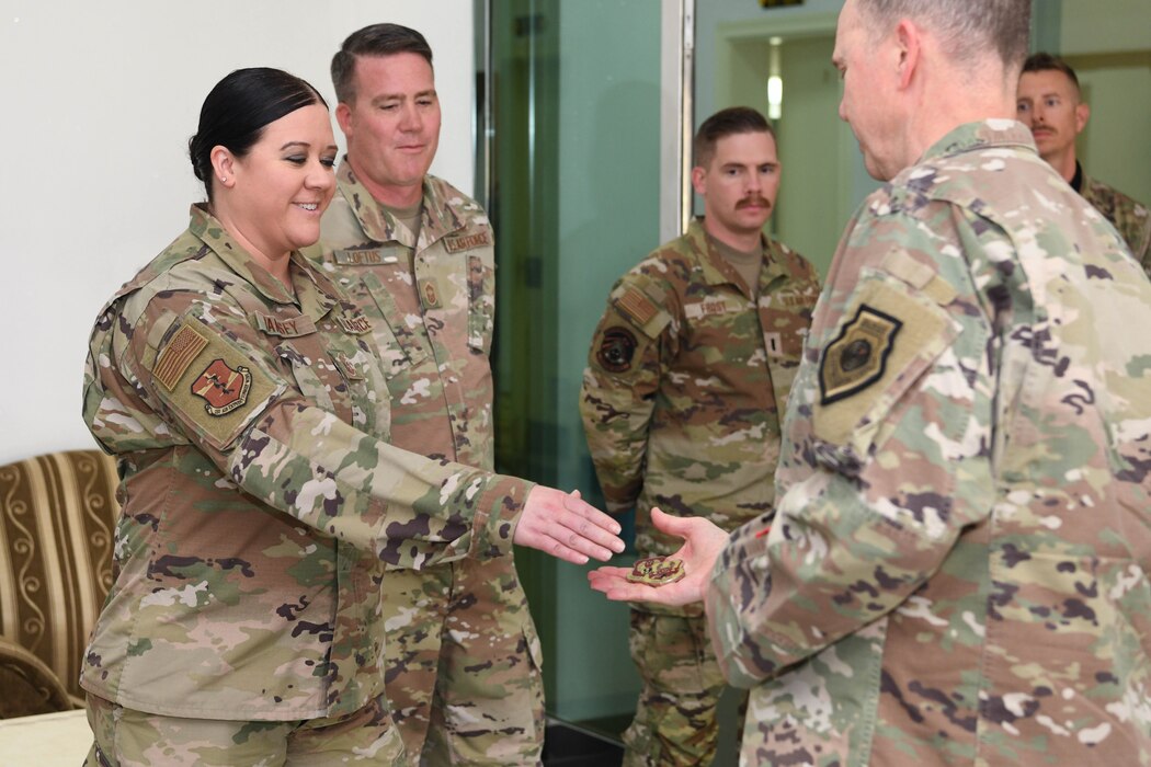 Master Sgt. Holly Ramsey, an administrative assistant assigned to the 380th Air Expeditionary Wing special staff, receives a challenge coin from Lt. Gen. Gregory M. Guillot, the Ninth Air Force (Air Forces Central) commander June 3, 2022 at Al Dhafra Air Base, United Arab Emirates. Ramsey was recognized for standing up the administrative cell during the wing's transition from group commanders to a wing level “A-Staff.”