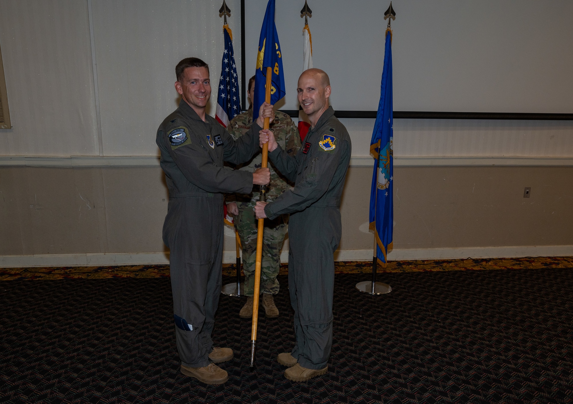 Two military members conduct a ceremony with a guidon (flag)