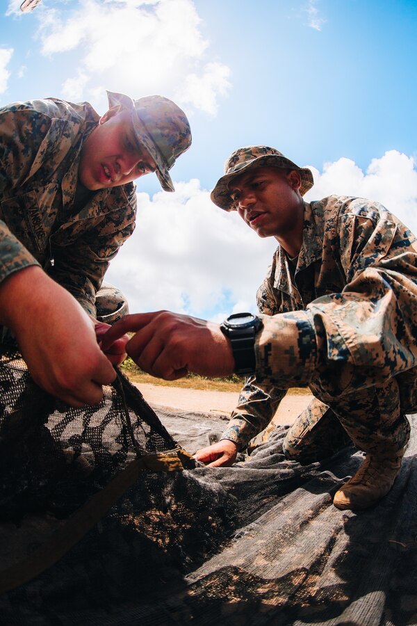 U.S. Marines with Headquarters Company, 3d Marine Littoral Regiment, 3d Marine Division, set up camouflage netting at Marine Corps Training Area Bellows, Hawaii, May 30, 2022. Marines with 3d MLR, Headquarters, conducted fundamental field training to refresh, sharpen, and build critical knowledge within operational environments. (U.S. Marine Corps photo by Cpl. Patrick King)
