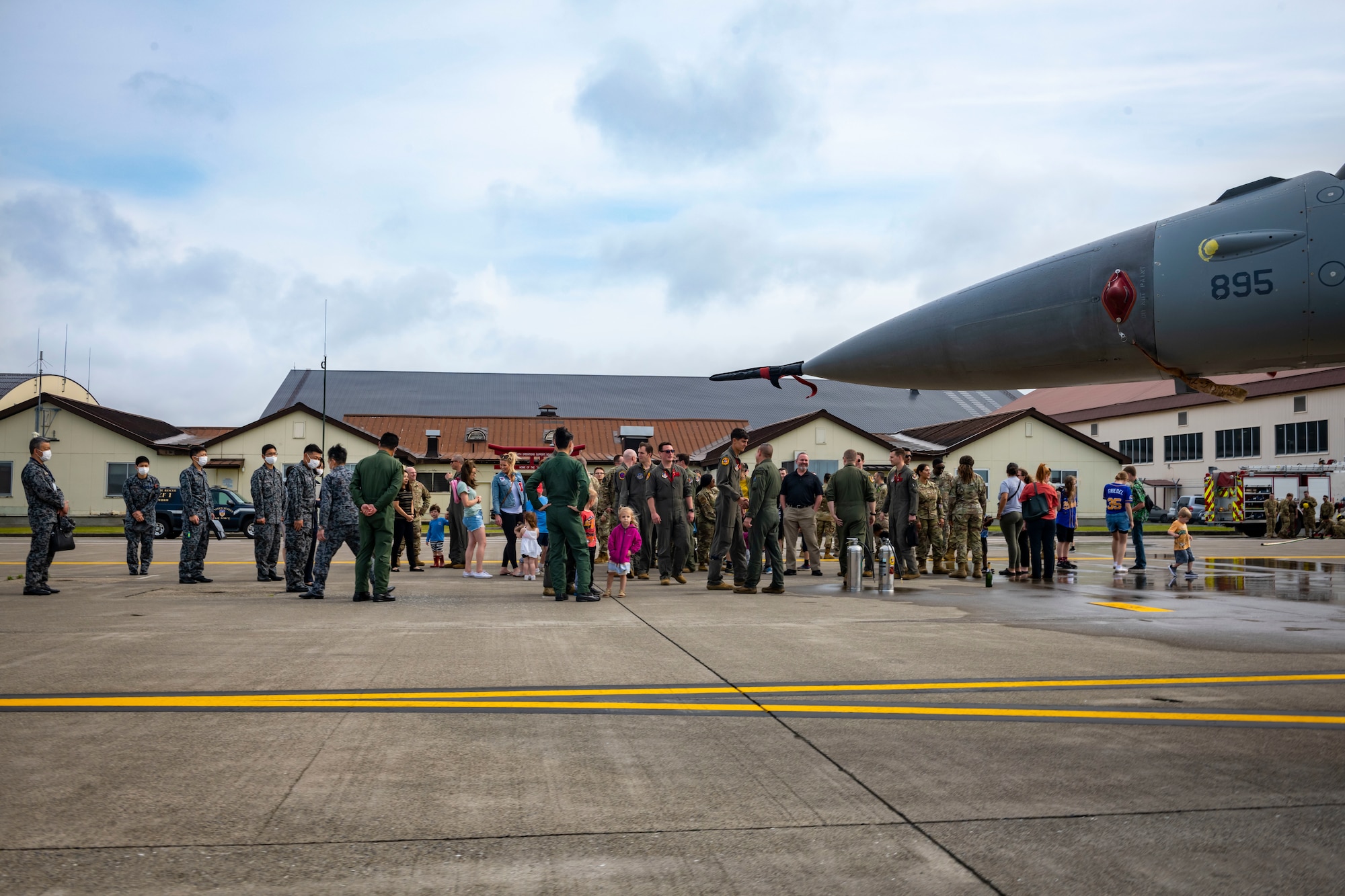 F-16 Fighting Falcon sits on a runway as U.S. and Japanese military members and civilians stand in the background.