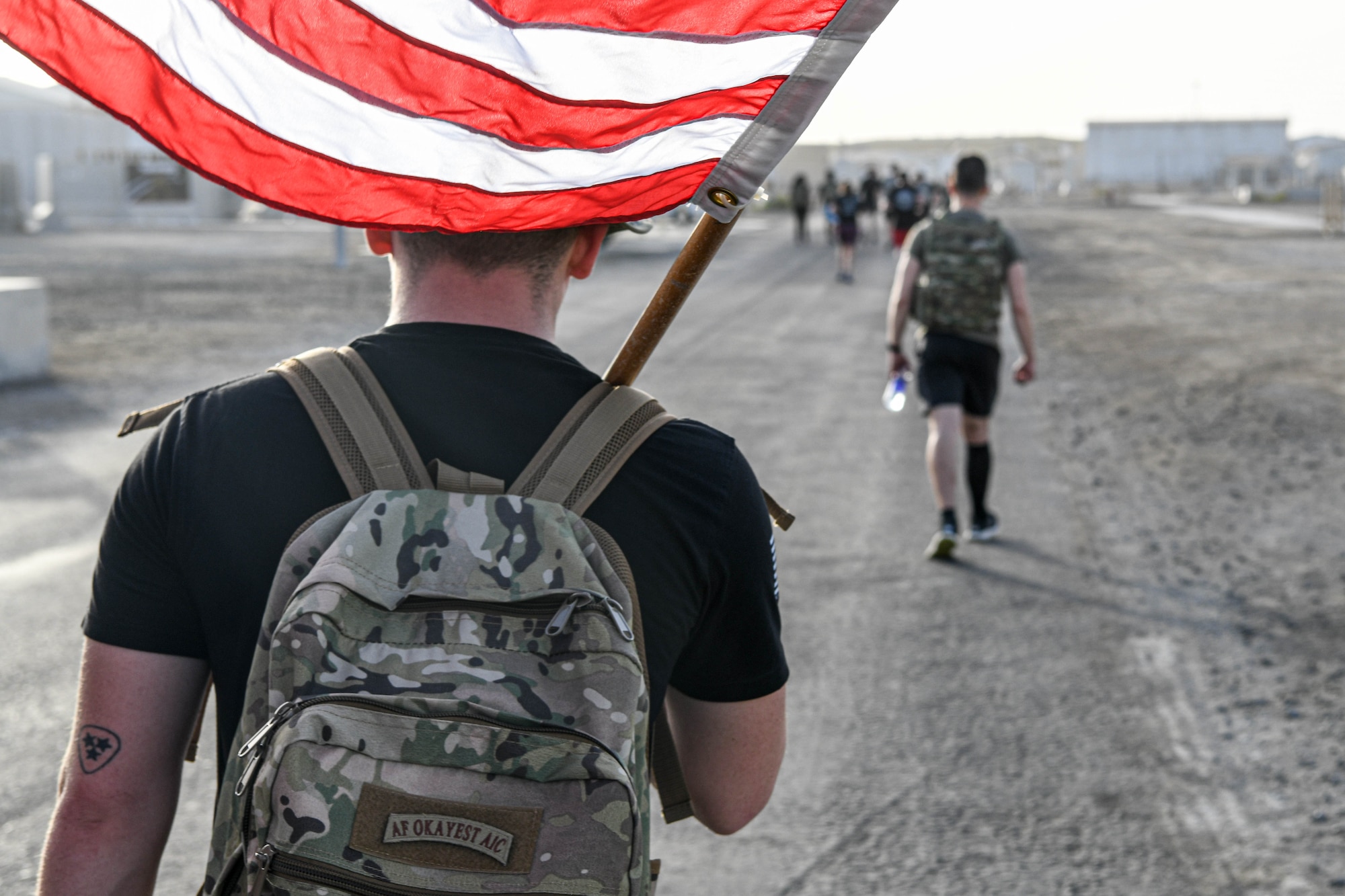 An Airman with the 380th Air Expeditionary wing carries the American flag during a memorial ruck and run event during Police Week, May 20th, 2022 at Al Dhafra Air Base, United Arab Emirates. In 1962, President John F. Kennedy signed a proclamation which designated May 15th as National Peace Officers Memorial Day, and the week in which it falls as National Police Week. Since the first service memorial gathering in Senate Park, Washington D.C., U.S. agencies across the nation and abroad have held events to honor fallen officers and acknowledge their sacrifices.