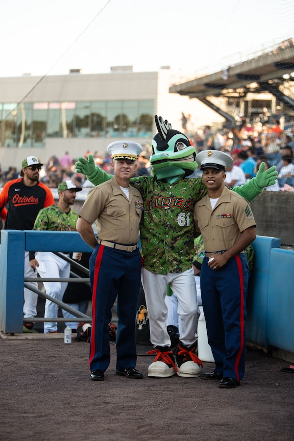 U.S. Marine Corps Col. Trevor Hall, left, Assistant Chief of Staff and Sgt. Jonathan T. Howard, right, a legal services specialist, both with Fleet Marine Force, Atlantic (FMFLANT), Marine Forces Command (MARFORCOM), Marine Forces Northern Command (MARFOR NORTHCOM), meet Triton, the Norfolk Tides minor-league baseball mascot, at Harbor Park Stadium, Norfolk, Virginia, June 18, 2022. U.S. Marines with FMFLANT, MARFORCOM, MARFOR NORTHCOM participated in the baseball game to represent the Marine Corps presence in Naval Station Norfolk, the biggest naval base in the world. Due to the military being an integral part of the Hampton Roads community, the Norfolk Tides hosts several military appreciation nights and military themed seasons in honor of the U.S. Armed Forces. (U.S. Marine Corps photo by Lance Cpl. Angel Alvarado)