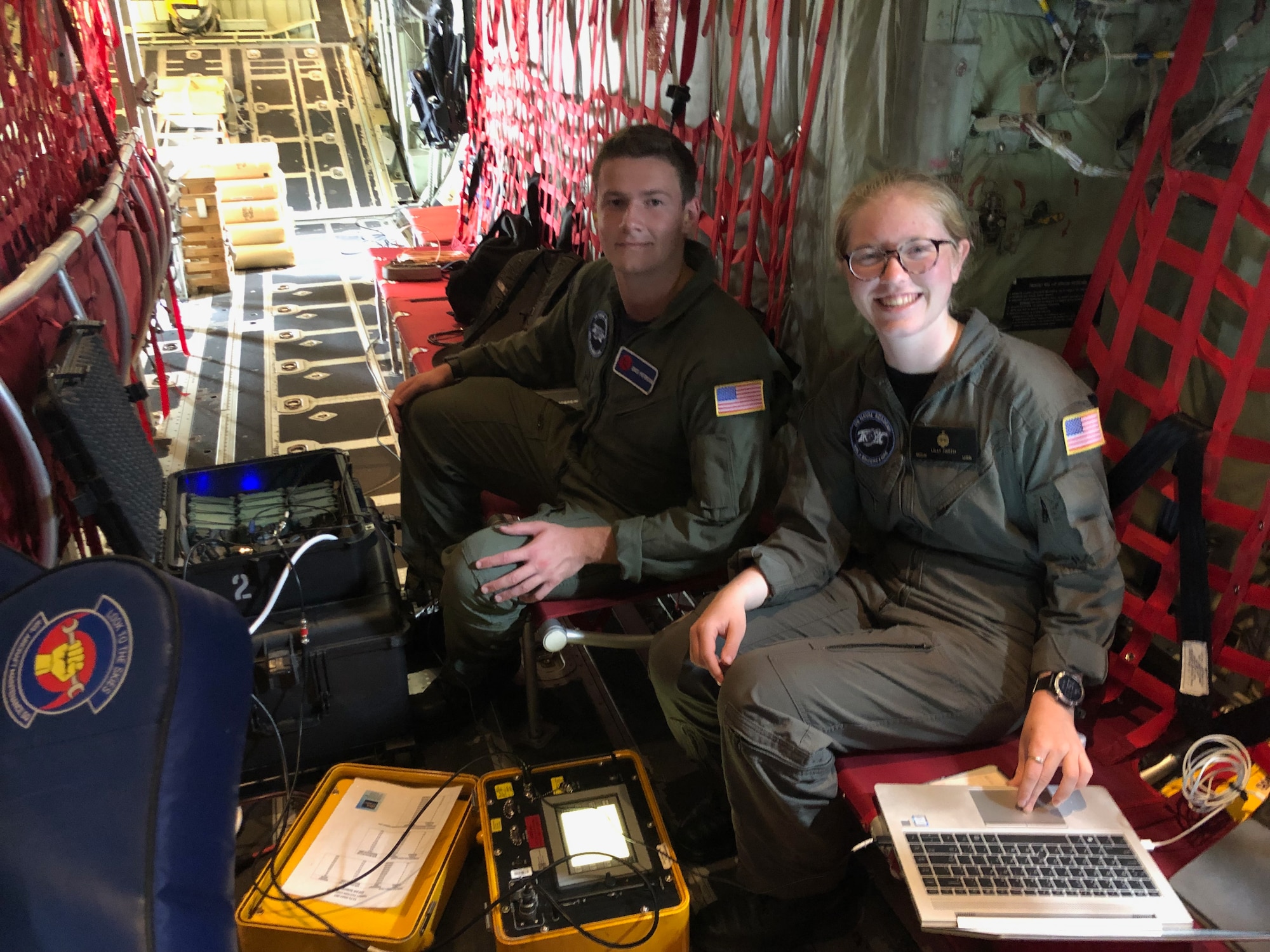 Two midshipment sit in a WC-130J aircraft with computers and other technology equipment strewn in front of them