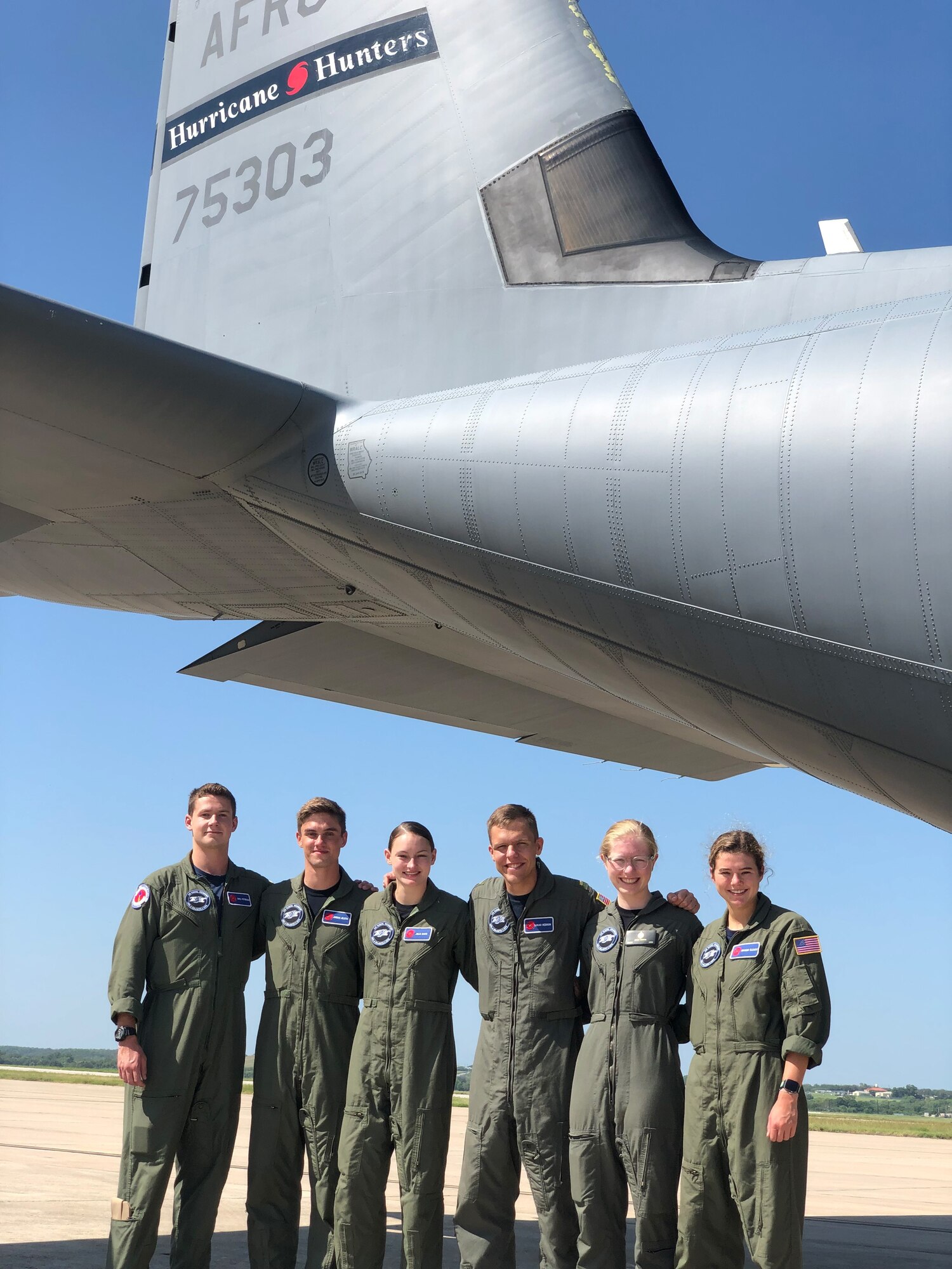 Six Midshipmen stand in front of the tail of a WC-130J Super Hercules aircraft