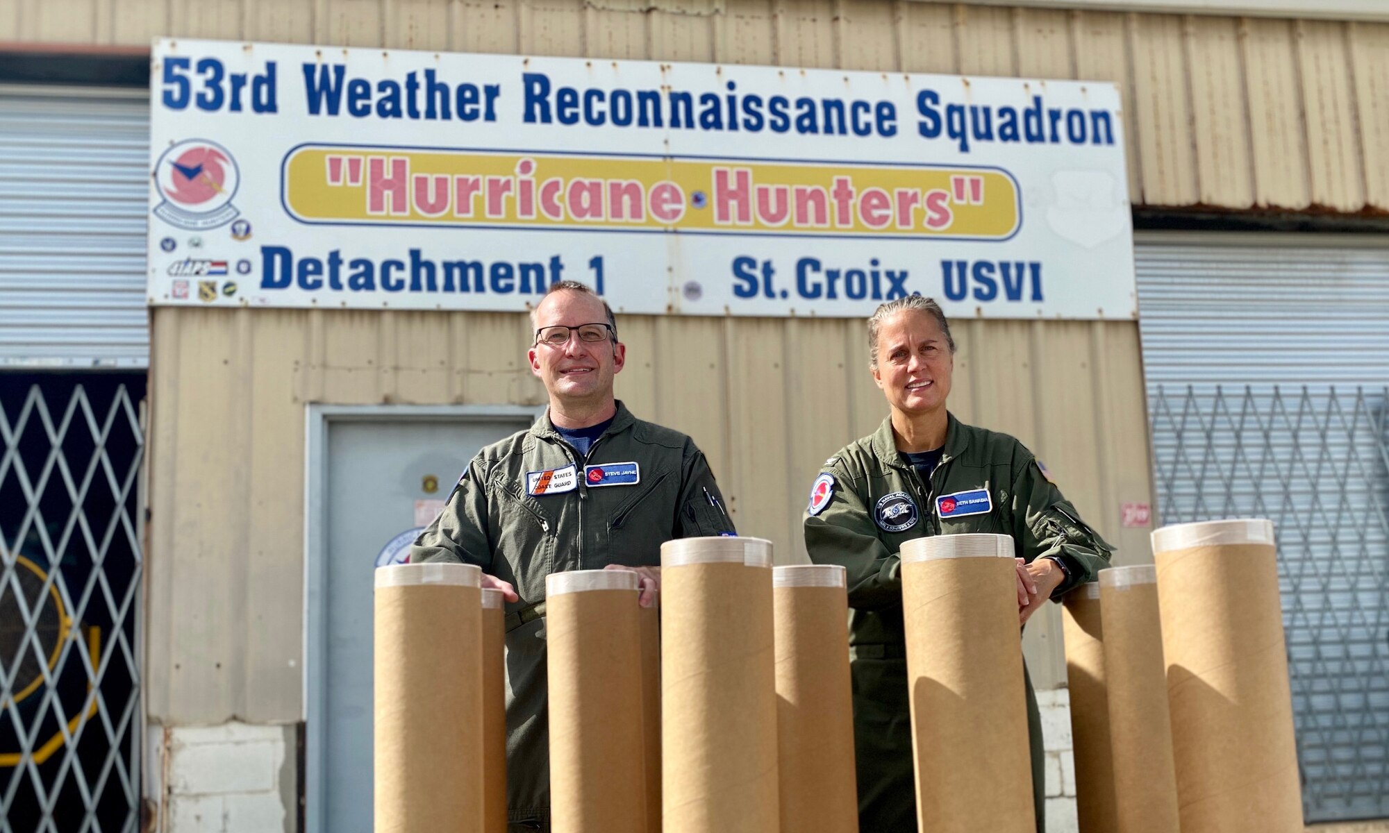 Senior Chief Jayne and Navy Capt. Sanabia pose in front of a sign that says "53rd Weather Reconnaissance Squadron Hurricane Hunters, Detachment 1, St Croix, USVI"