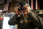 a man with a helmet holds goggles to his eyes.