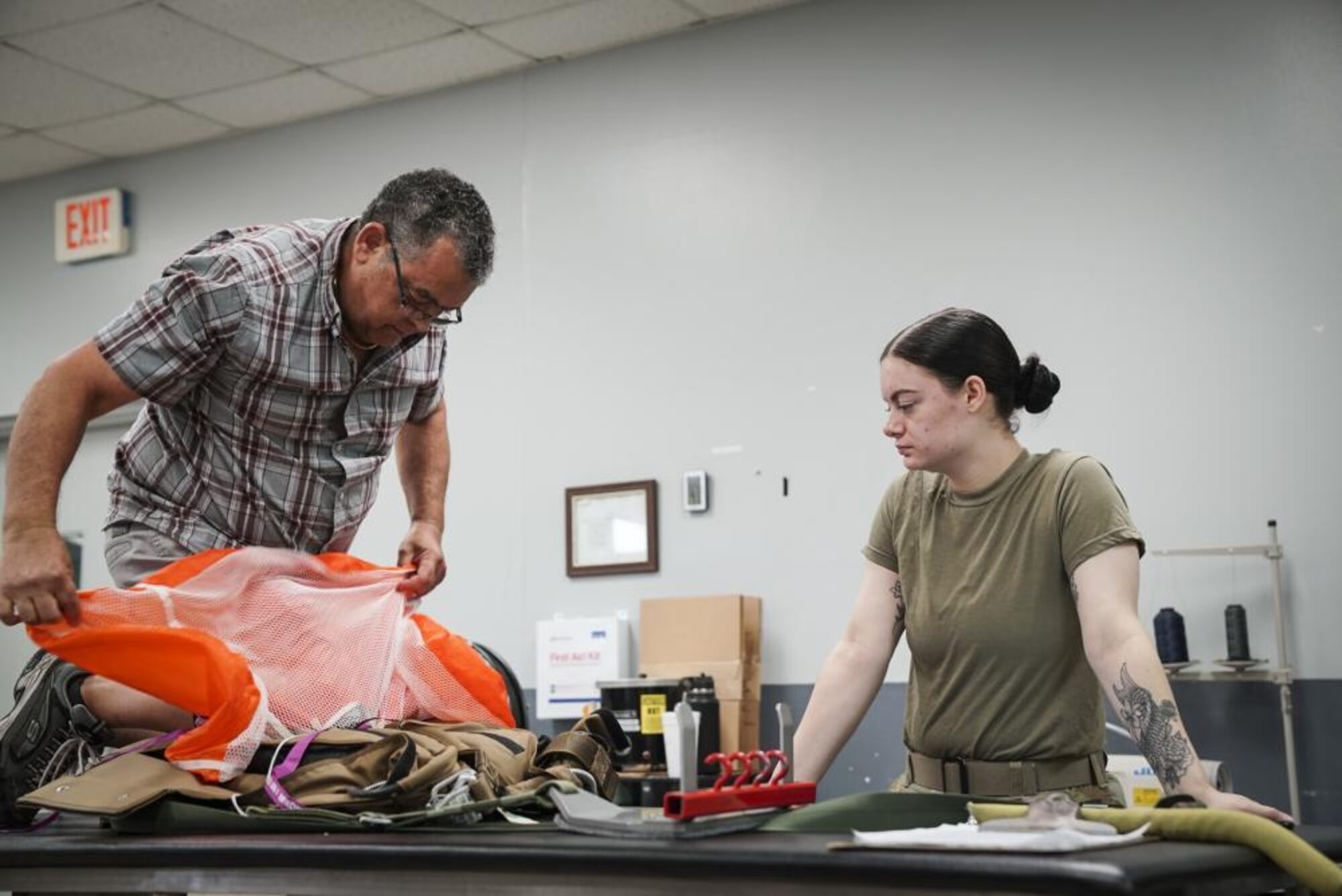 U.S. Air Force Master Sgt. (ret.) Gerald Rodrigues, a 1st Special Operations Support Squadron training manager, and Airman Kennedy Salvetti, a 1st Special Operations Support Squadron aircrew flight equipment specialist, demonstrate the proper method of packing a pilot chute, at Hurlburt Field, Florida, June 14, 2022.
