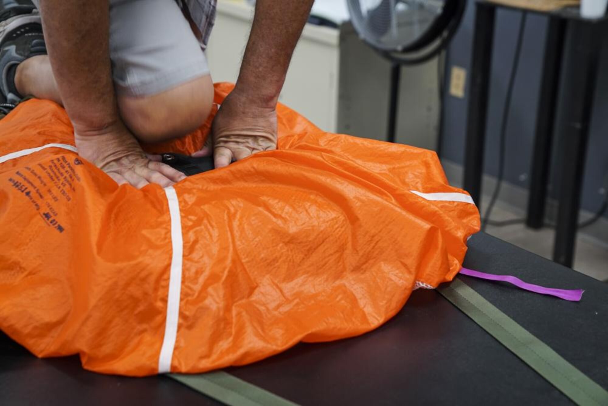 U.S. Air Force Master Sgt. (ret.) Gerald Rodrigues, a 1st Special Operations Support Squadron training manager, compresses the spring of the pilot chute for packing, at Hurlburt Field, Florida, June 14, 2022.