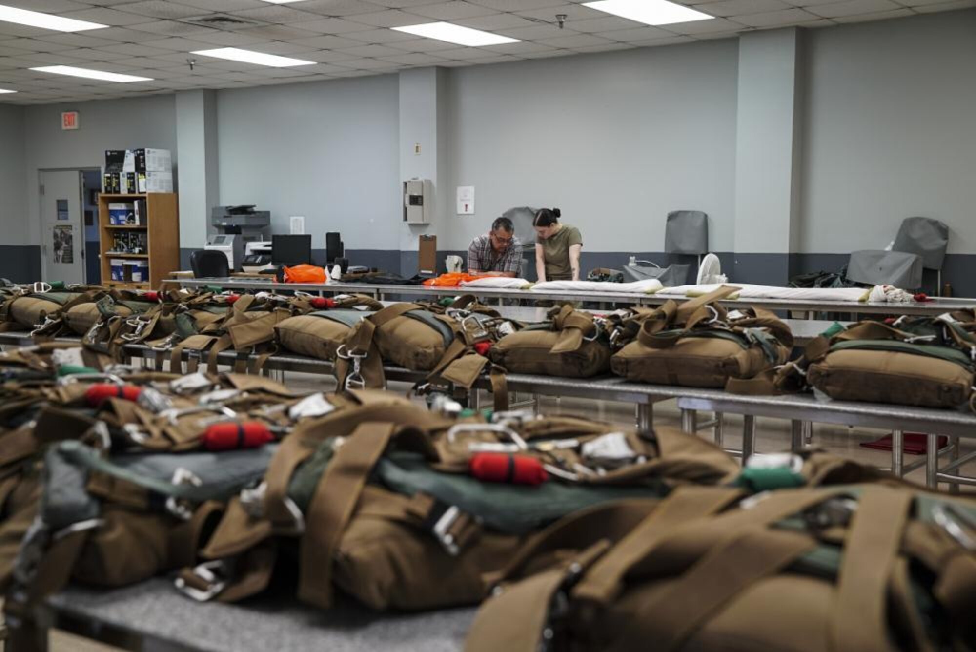 U.S. Air Force Master Sgt. (ret.) Gerald Rodrigues, a 1st Special Operations Support Squadron training manager, and U.S. Air Force Airman Kennedy Salvetti, a 1st Special Operations Support Squadron aircrew flight equipment specialist, review the technical orders for packing the low-profile parachute, at Hurlburt Field, Florida, June 14, 2022.