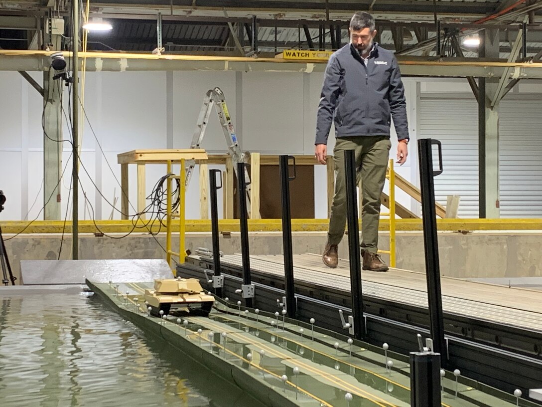 Dr. Duncan Bryant, a research hydraulic engineer with the U.S. Army Engineer Research and Development Center’s (ERDC) Coastal and Hydraulics Laboratory, observes a model tank crossing a scale model of the Improved Ribbon Bridge (IRB), Feb. 24, 2022. Researchers at the ERDC are using physical modeling as part of an effort to test the high military load capacity vehicle weight limits of the IRB to determine under what operational conditions they can safely cross.