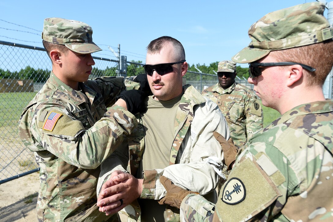 U.S. Army Reserve Spc. Joaquin Miranda, left, Corrections Officer, 420th Military Police Company, searches Pfc. Michael Sobota, center, Aircraft Electrician, 530th Military Police Battalion, participating as a role-player, before entering the Theater Detention Facility at the Spartan Warrior Three Training Exercise, June 19, 2022 on Fort McCoy, Wisconsin.