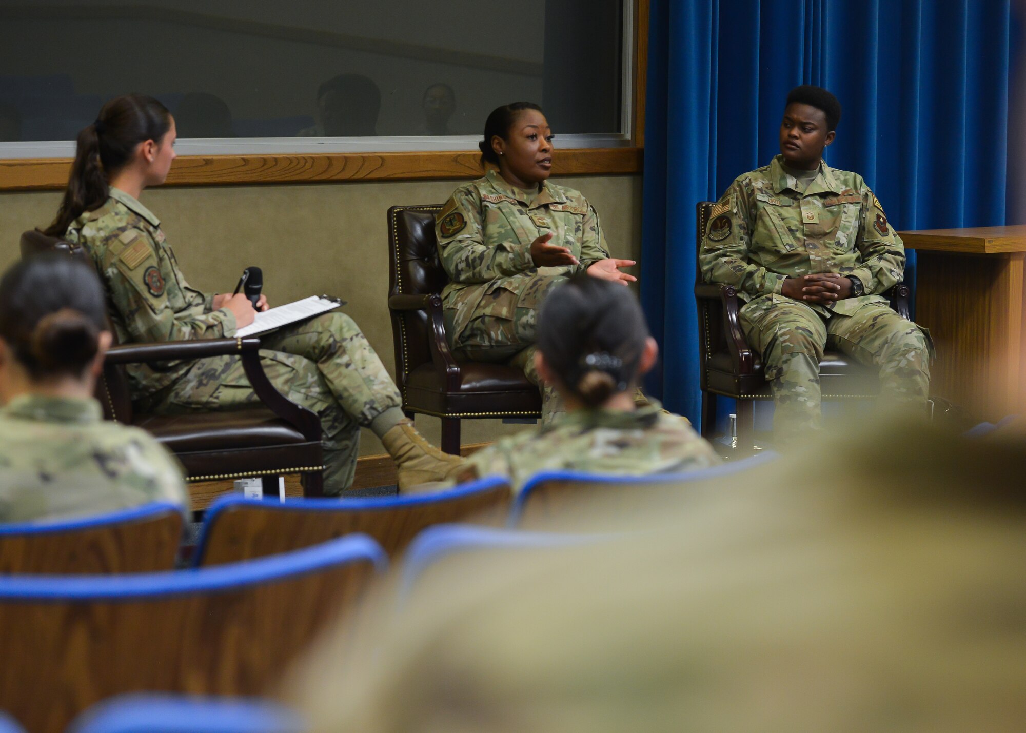 A group of women talk on stage.