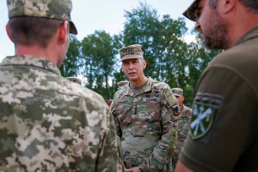 A four-star general speaks with a group of uniformed service members.