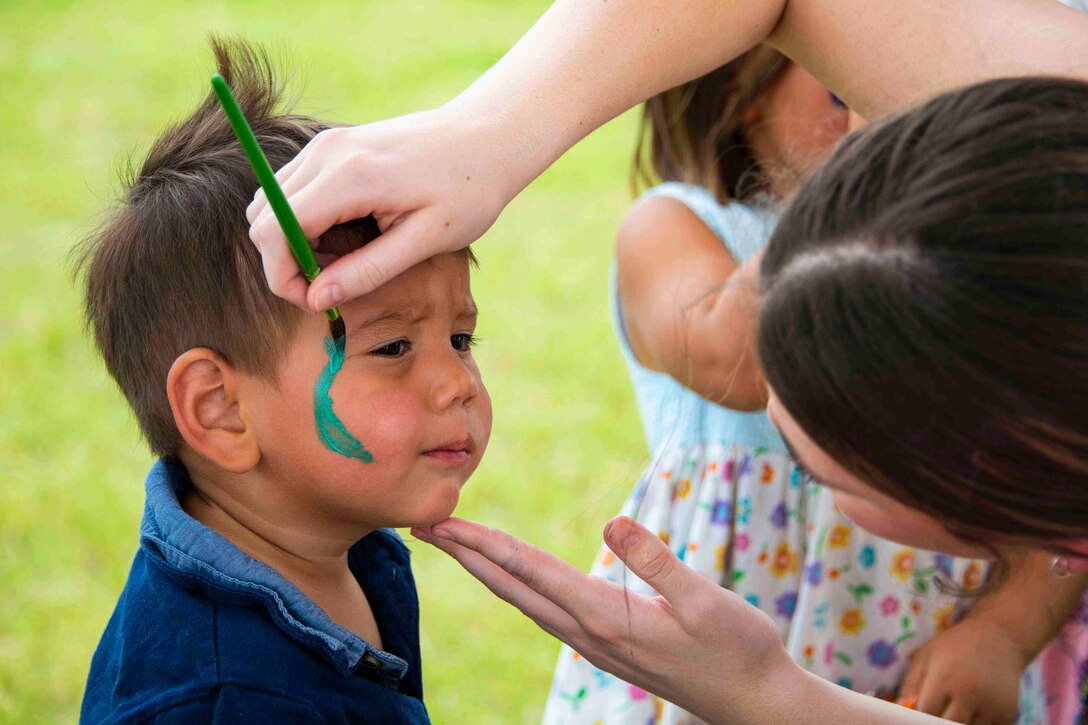 A child gets green paint painted on his face.