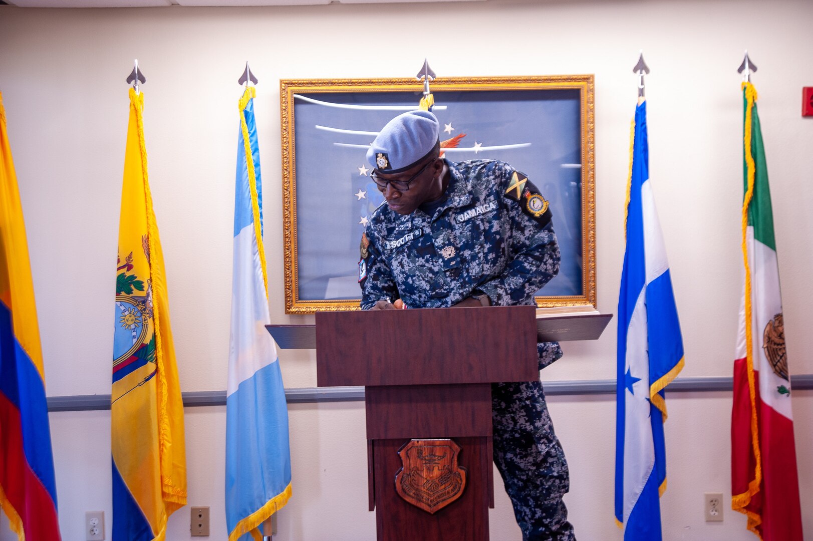 Jamaican Defence Force warrant officer signs a guestbook on top of a podium