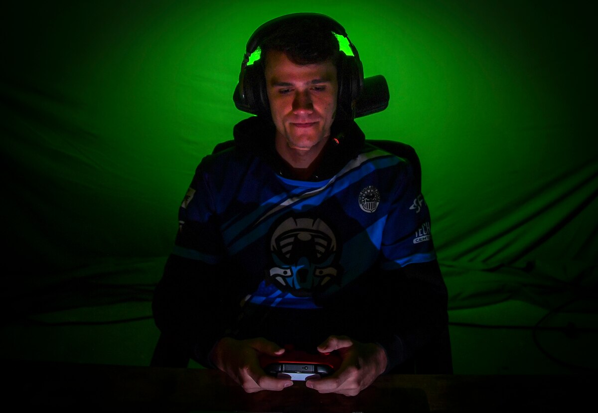 A gamer poses for a photo with a green background.