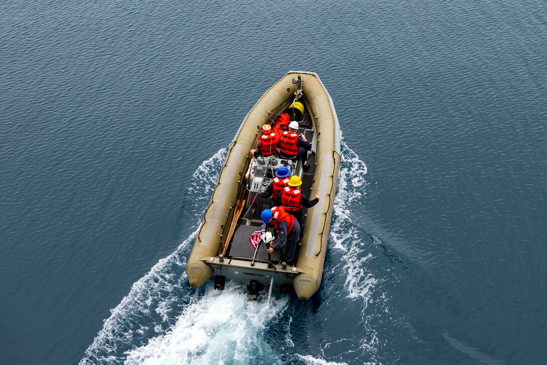 Sailors operate a small inflatable boat in the water.