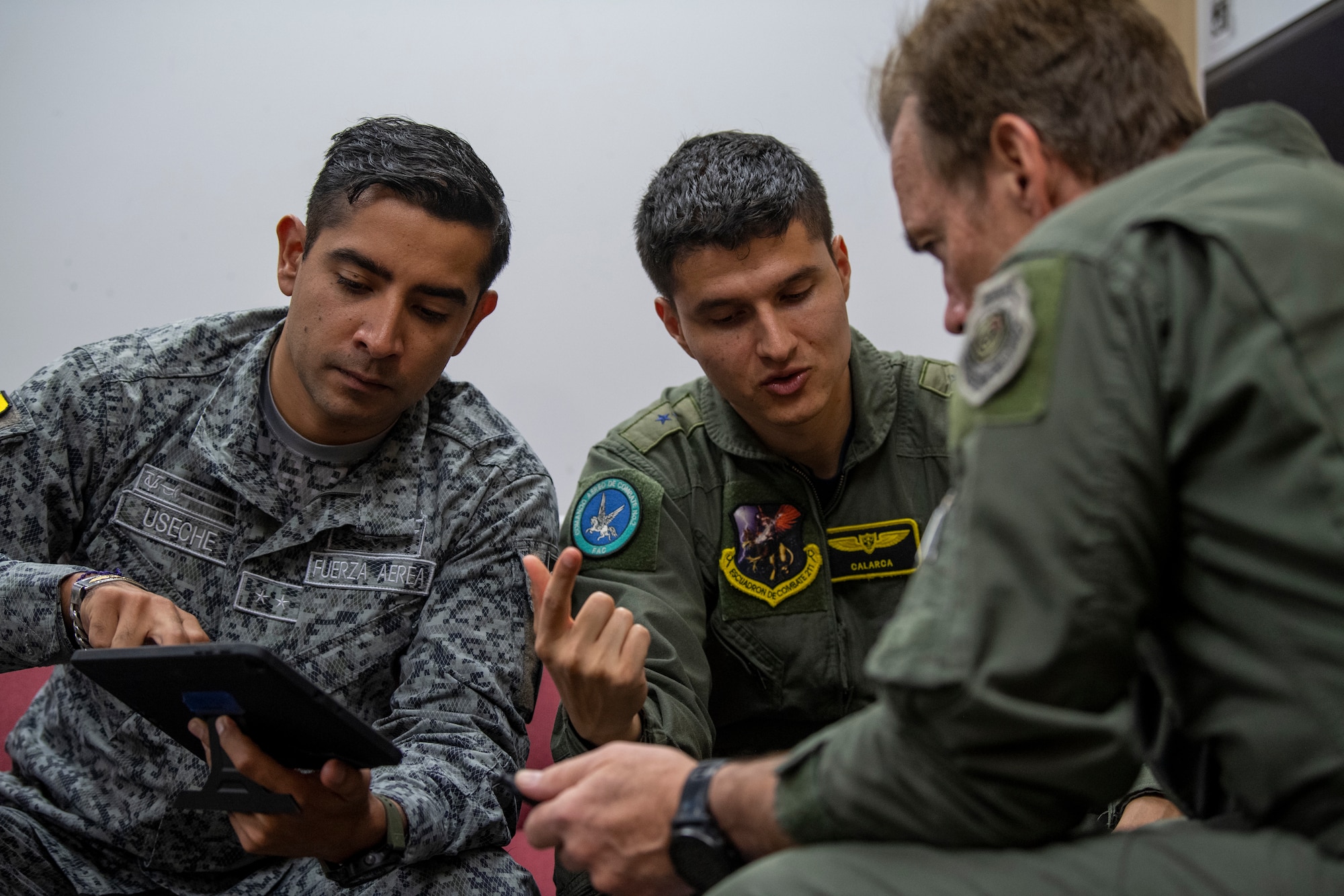 Colombian air force 1st Lt. Gabriel Enrique Useche, joint terminal attack controller, left; Colombian air force 1st Lt. Juan Pablo Valencia, pilot, center; and Craig Fisher, 81st Fighter Squadron supervisory instructor pilot, debrief after landing at Avon Park Air Force Range, Florida, May 10, 2022. The U.S. Air Force partnered with Colombia, Tunisia, Nigeria, and Thailand to co-develop tactics, techniques and procedures to combat violent extremist organizations while demonstrating the capabilities of the Airborne Extensible Relay Over-Horizon Network. (U.S. Air Force photo by Airman 1st Class Deanna Muir)
