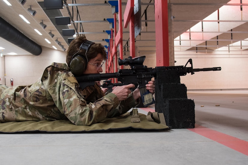A female service member shoots a military weapon.