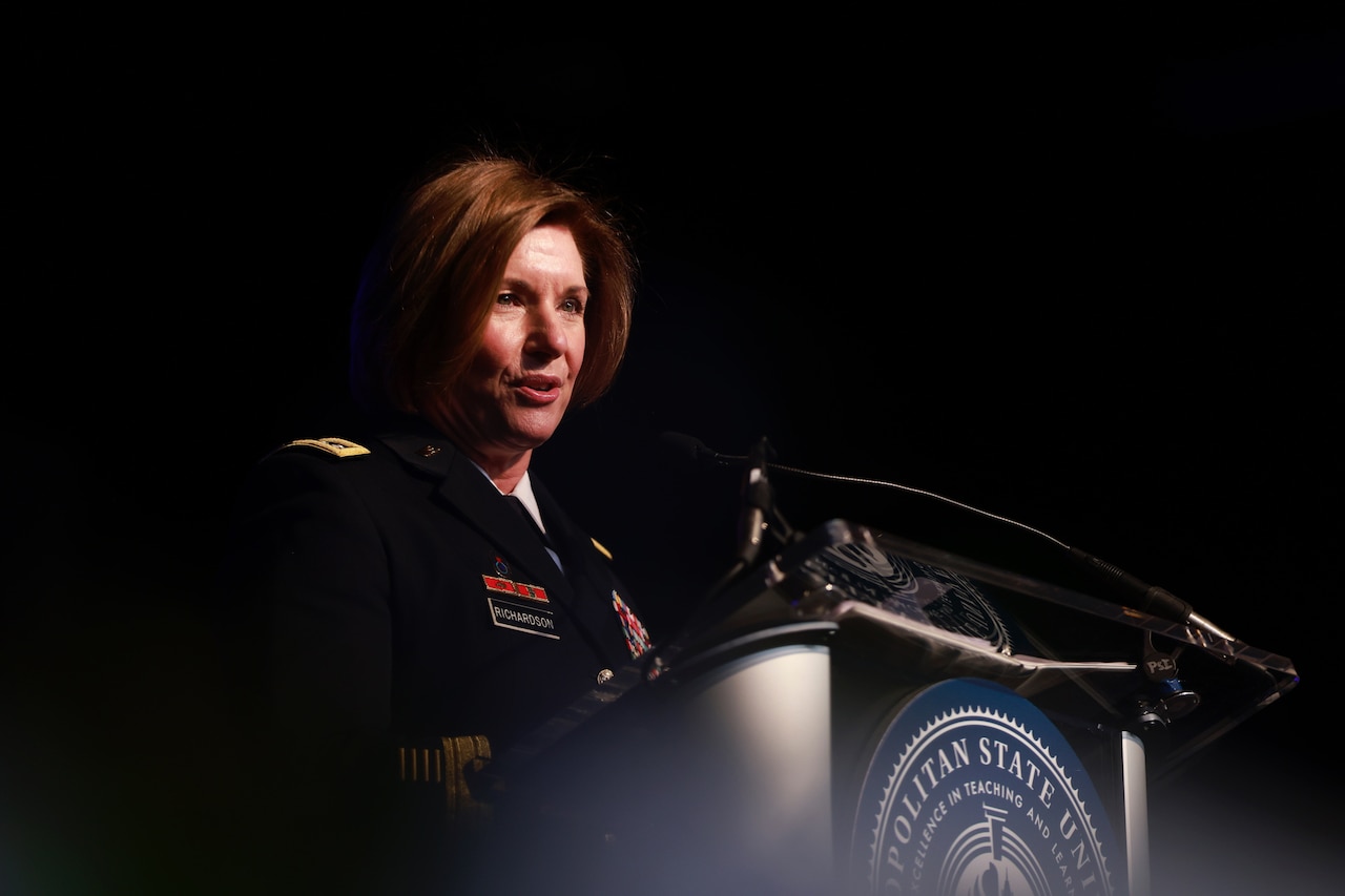 A female military leader speaks at a ceremony.