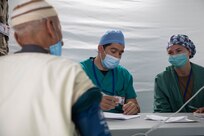 U.S. Air Force Physician Maj. Rozlyn Poray and a Moroccan physician assess the medical condition of a Moroccan man at the Humanitarian Civic Assistance (HCA) center in Taliouine, Morocco, June 21, 2022, during African Lion 22.