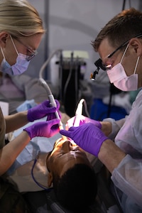 U.S. Army Spc. Rebecca Sipe and a Maj. Boyd Bandy clean the teeth of a Moroccan man at the Humanitarian Civic Assistance (HCA) center in Taliouine, Morocco June 22, 2022