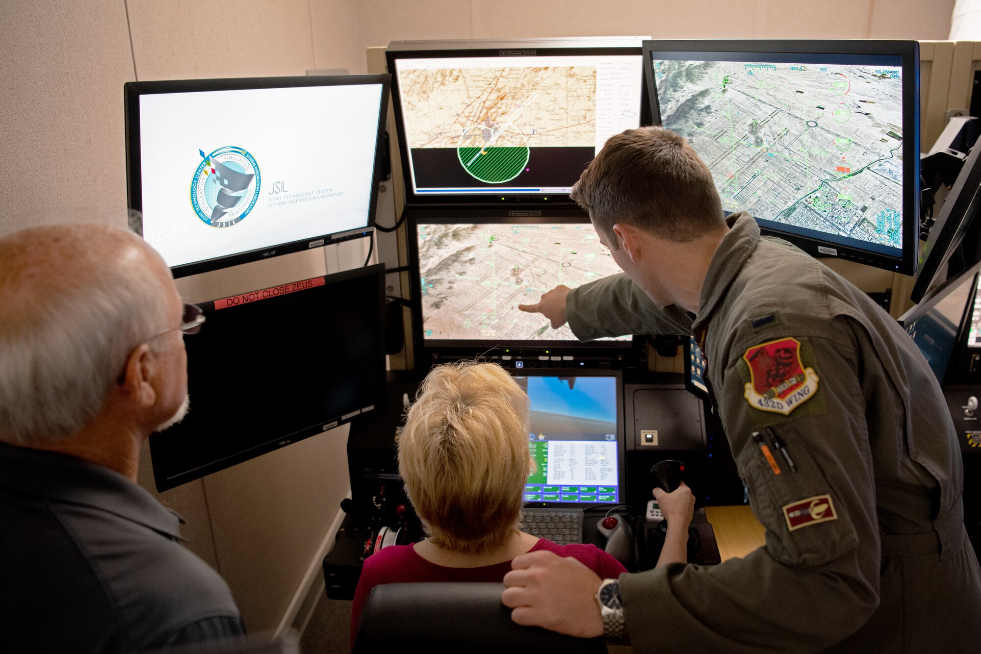 U.S. Air Force 1st Lt. Logan, MQ-9 Reaper pilot, right, directs Tina McKiethan, 77th Fighter Generation Squadron honorary commander, center, in a simulator during an immersion tour at Shaw Air Force Base, S.C. June 22, 2022. MQ-9 operations are split into two components: the pilot, who sits on the left and controls the aircraft, and the sensor operator, who sits on the right and controls targeting systems. (U.S. Air Force photo by Staff Sgt. Kelsey Owen)