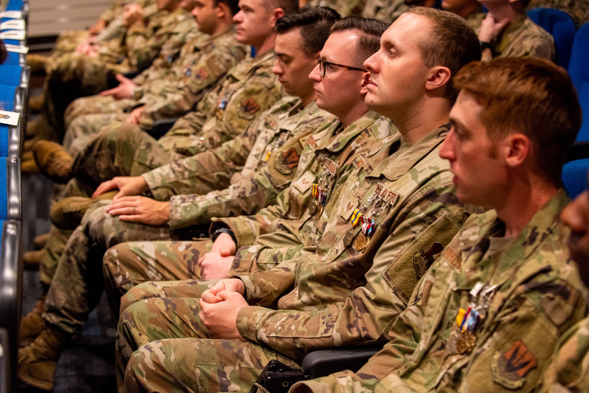 U.S. Air Force Airmen listen to a decoration citation reading during an awards ceremony at Moody Air Force Base, Georgia, May 31, 2022. The Personnel Recovery Task Force – Hamid Karzai International Airport team was comprised of more than 175 Airmen deployed from three different bases and 11 home station squadrons. (U.S. Air Force photo by Airman 1st Class Courtney Sebastianelli)
