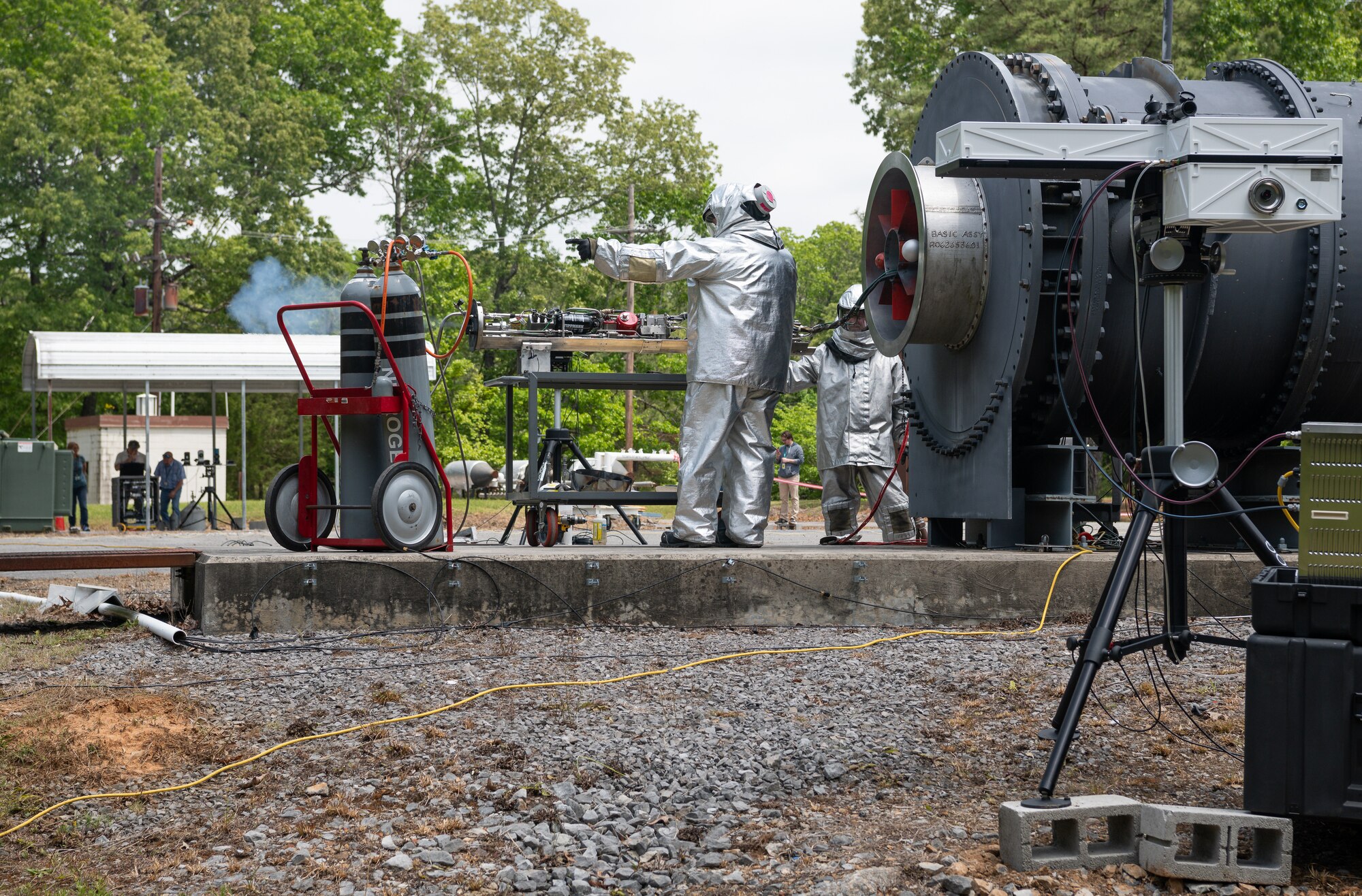 Two men in protective suits working on a towed airborne plume simulator fuel tank