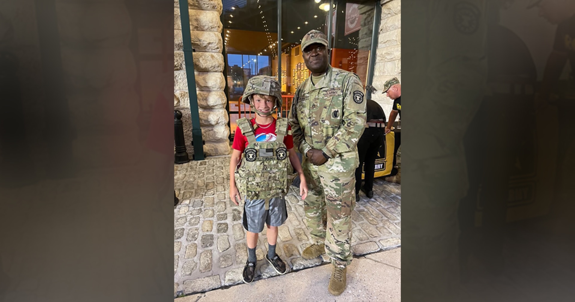 man in army uniform and boy wearing army gear pose for a photo.
