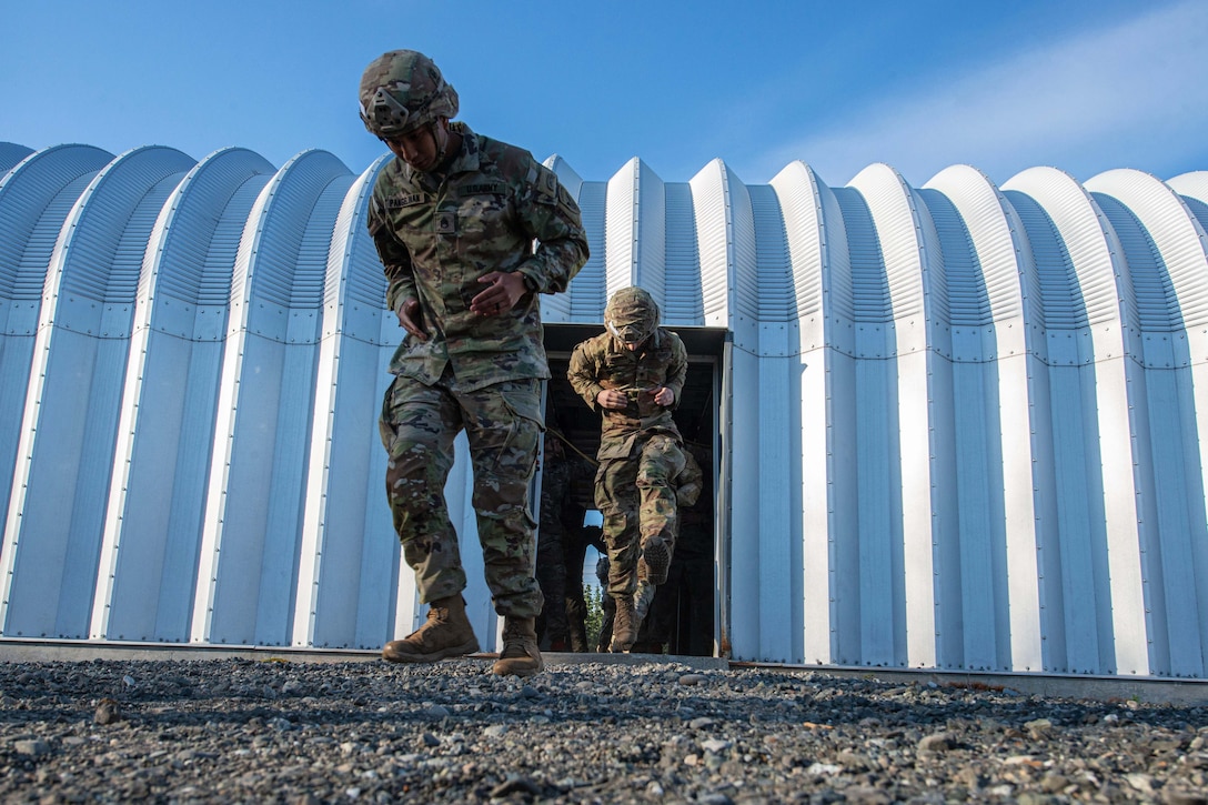 Service members walk out of a building in a line.