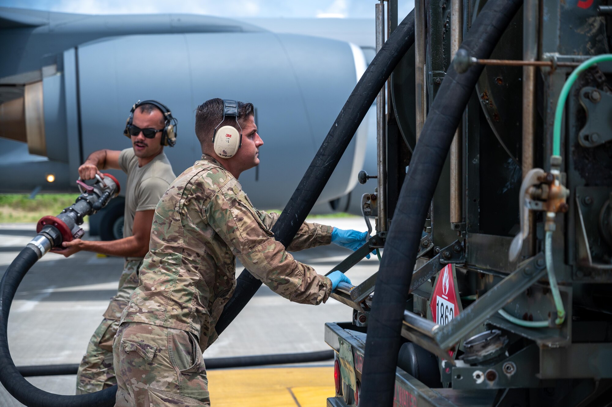 Airmen getting out a fuel hose from a fuel truck.