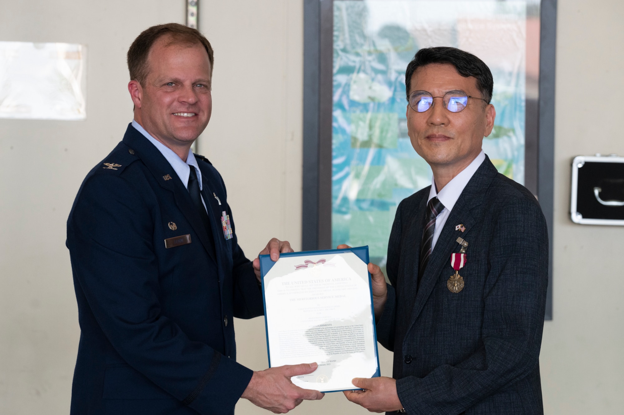 Col. Gary S. Floyd, 694th Intelligence Surveillance and Reconnaissance Group commander, left, presents retired Republic of Korea Air Force Chief Master Sgt. Kim Kyu-dong with a Meritorious Service Medal award at Osan Air Base, Republic of Korea, June 21, 2022.