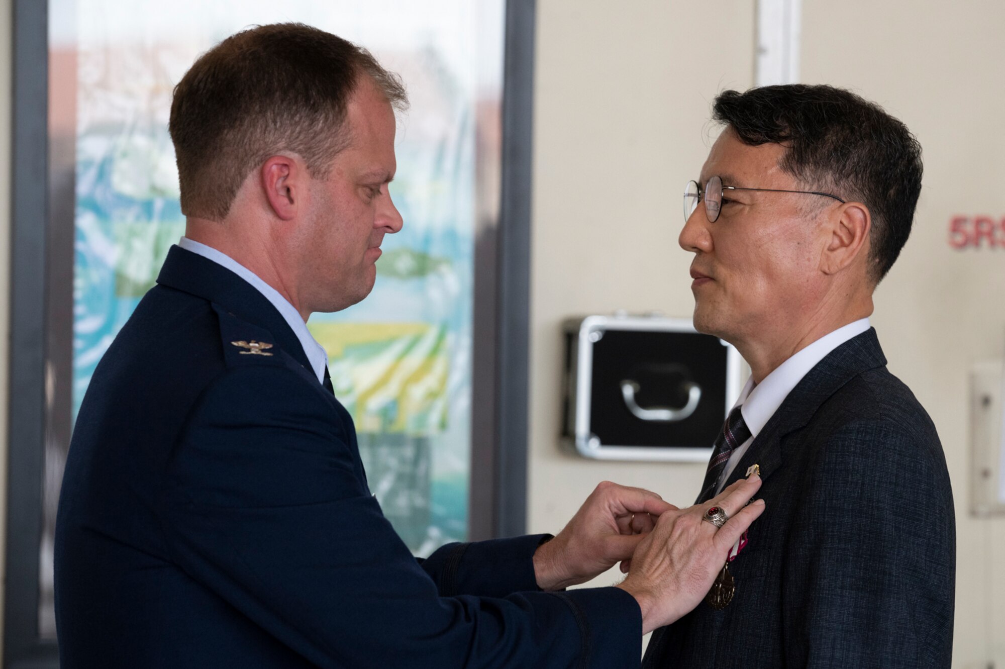 Col. Gary S. Floyd, 694th Intelligence Surveillance and Reconnaissance Group commander, left, pins a Meritorious Service Medal on retired Republic of Korea Air Chief Master Sgt. Kim Kyu-dong at Osan Air Base, Republic of Korea, June 21, 2022.