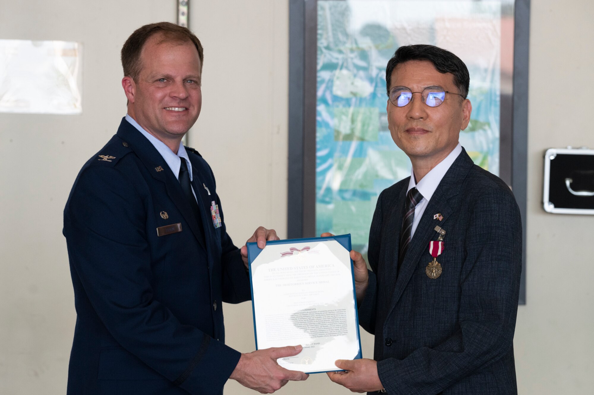 Col. Gary S. Floyd, 694th Intelligence Surveillance and Reconnaissance Group commander, left, presents retired Republic of Korea Air Force Chief Master Sgt. Kim Kyu-dong with a Meritorious Service Medal award at Osan Air Base, Republic of Korea, June 21, 2022.