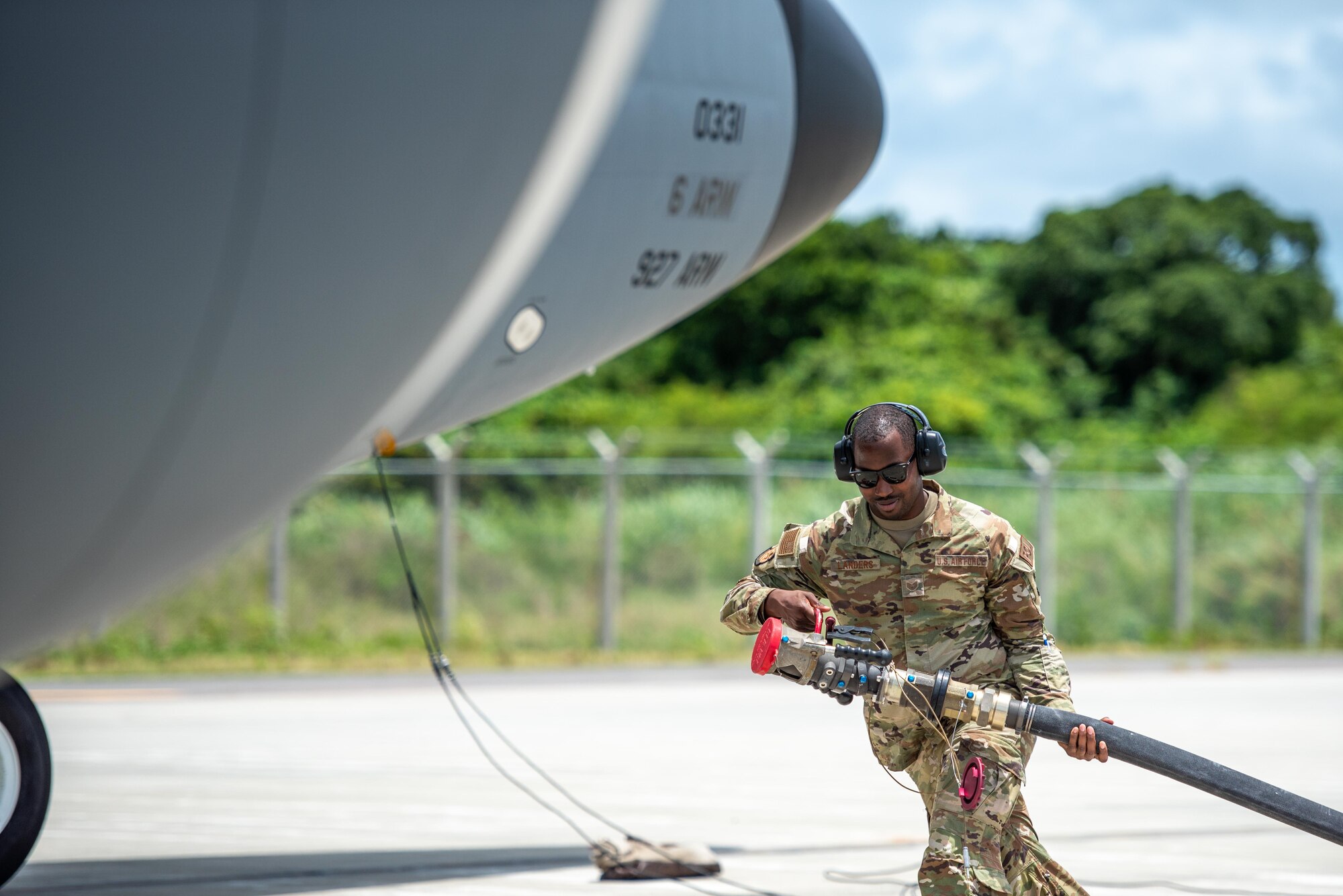 Airman dragging a fuel hose towards an aircraft