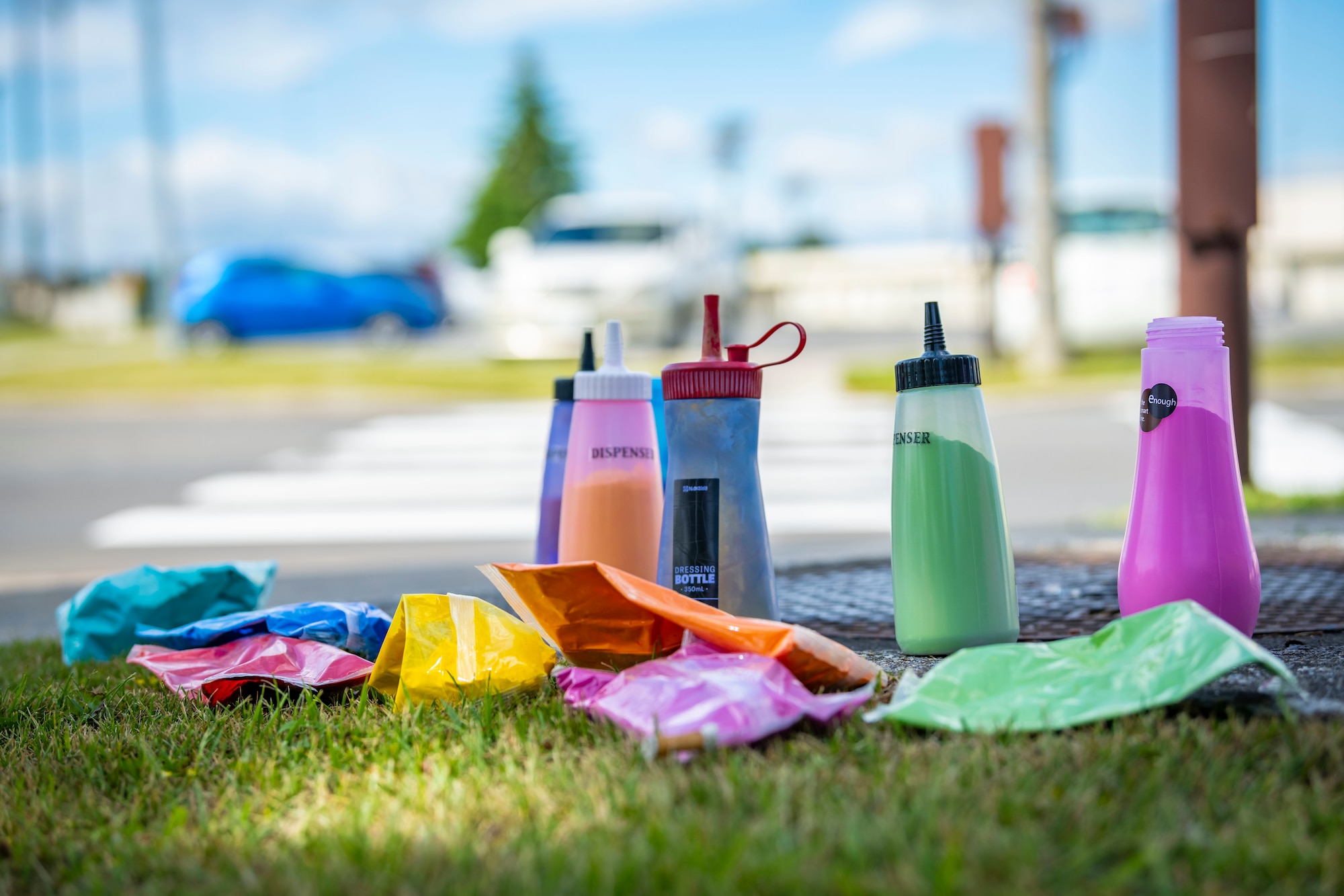 Bottles of colored powder sit on grass.