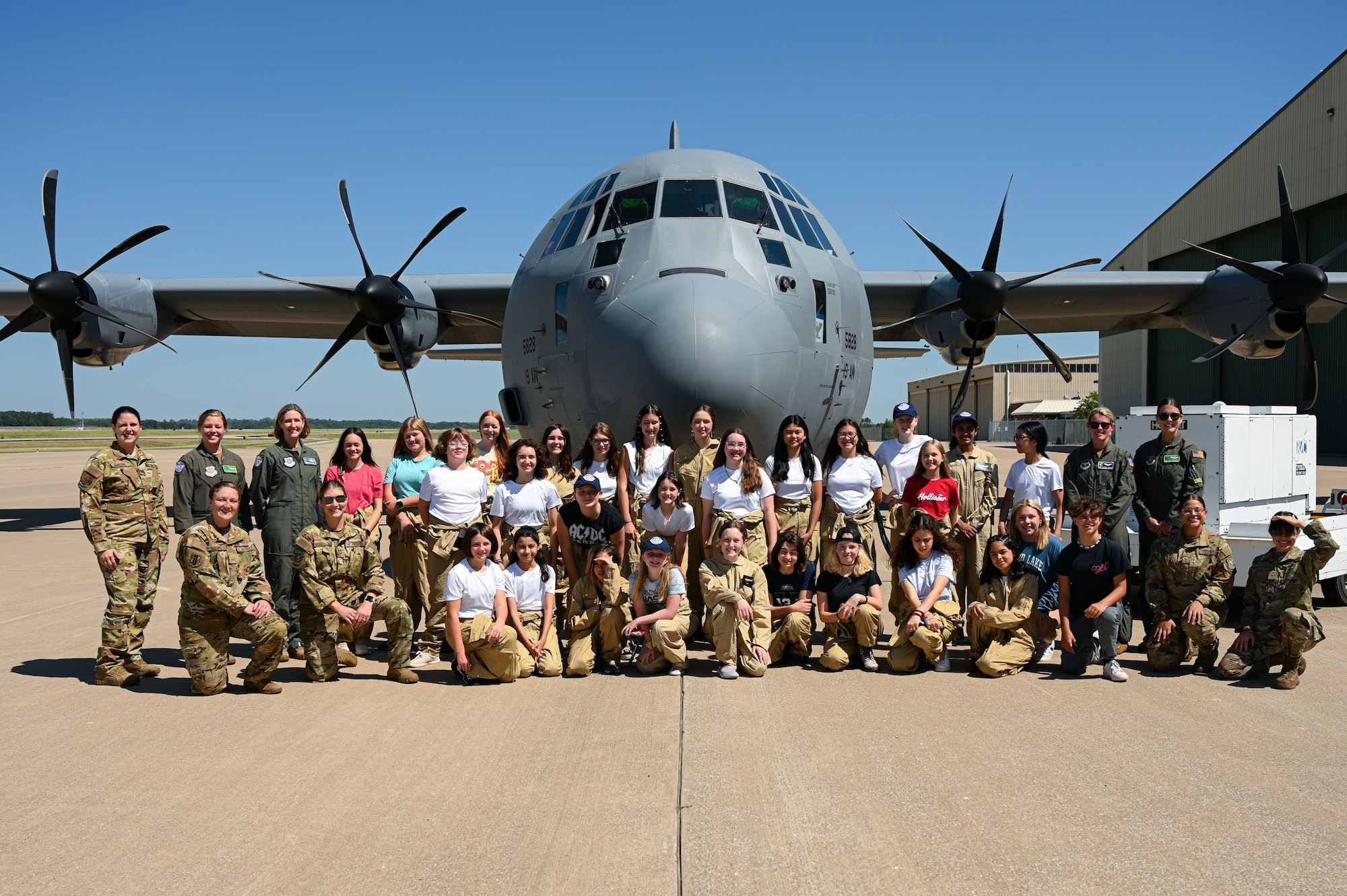Students and Airmen pose for a photo in front of a C-130J Super Hercules.