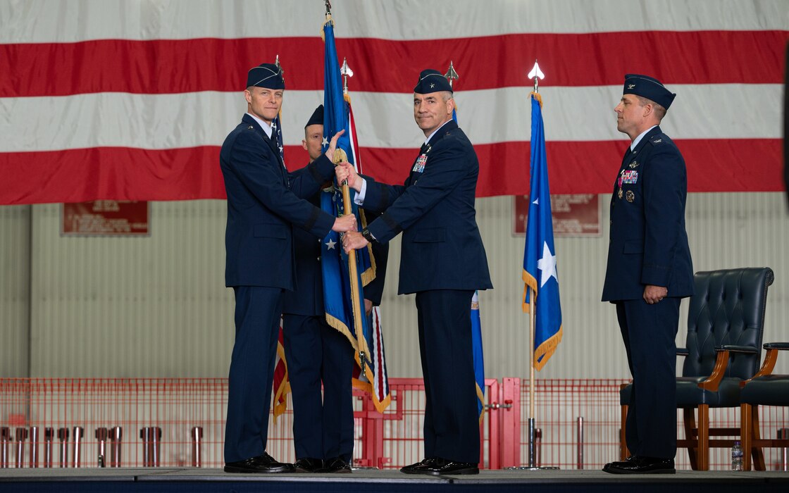 Photo of a guidon passing between two Airmen