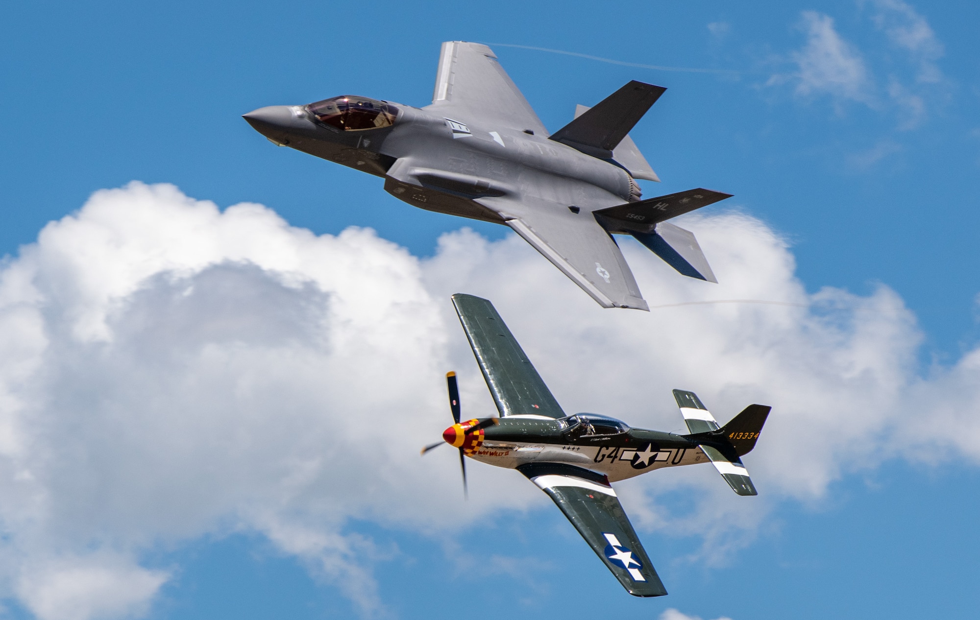 An F-35A and P-51 fly side by side in formation.