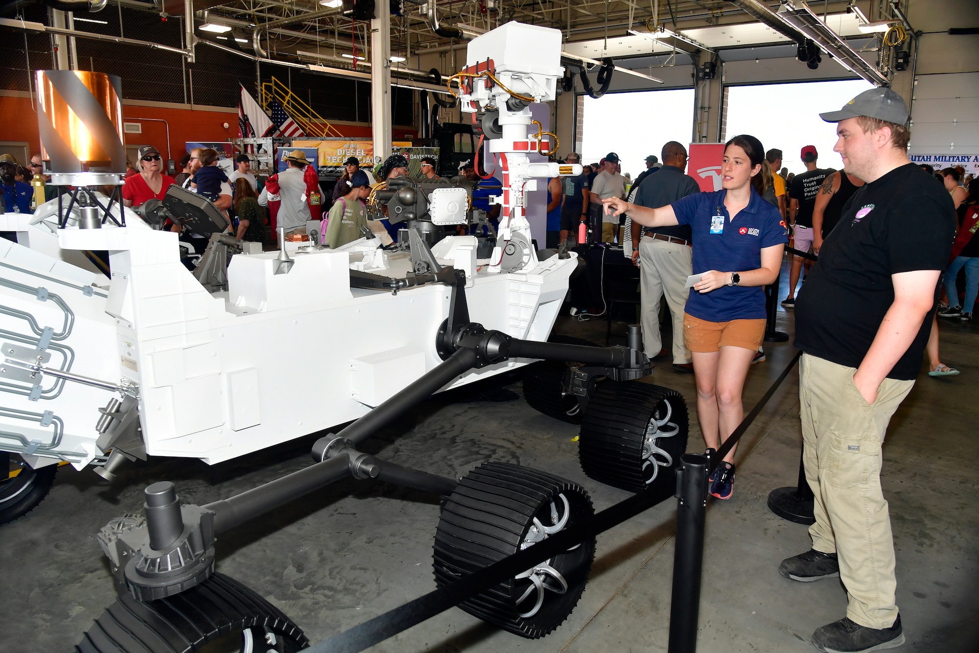 Brooklin Cohen points to the Mars rover on display while an event goer looks on.