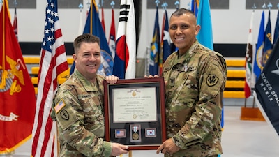 DLA Indo-Pacific Military Deputy Commander Army Col. Brian Donahue and Army Lt. Col. Jose Medina hold a plaque