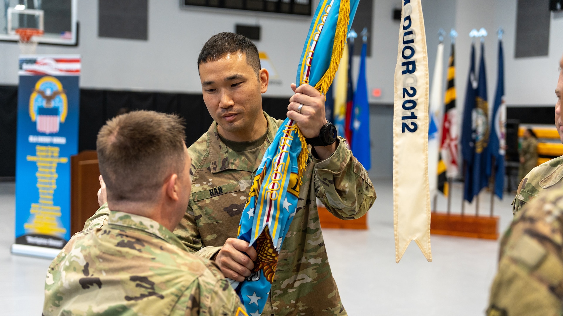 Army Lt. Col. Dennis Han hands the flag to DLA Indo-Pacific Military Deputy Commander Army Col. Brian Donahue