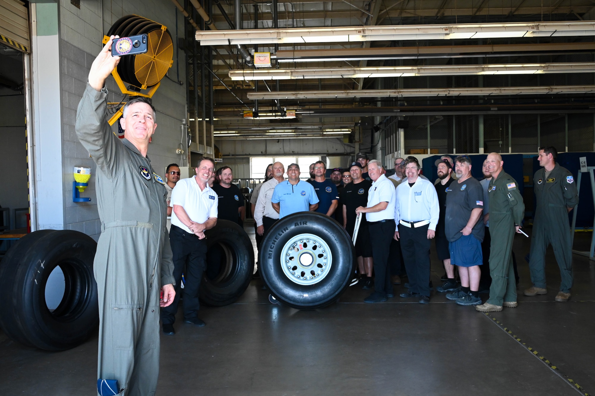 U.S. Air Force Maj. Gen. Craig D. Wills, 19th Air Force commander, takes a photo with 97th Maintenance Group members at Altus Air Force Base, Oklahoma, June 23, 2022. Wills visited the tire shop to learn about a new way of making KC-46 Pegasus tires. (U.S. Air Force photo by Senior Airman Kayla Christenson)